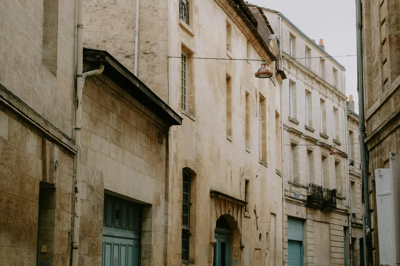 Quiet curving street between weathered stone buildings.