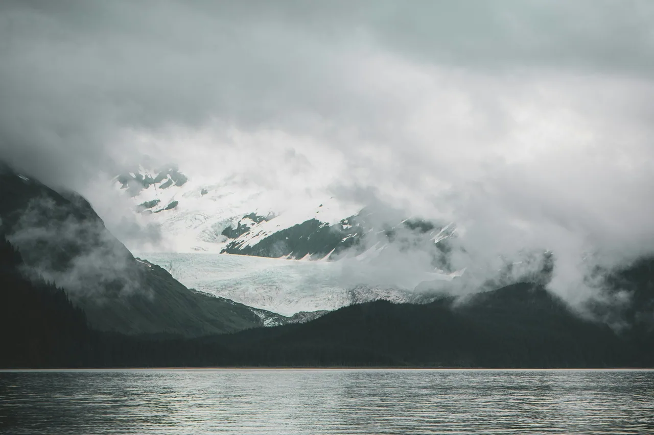 Mist-covered mountains reflected in a calm lake.